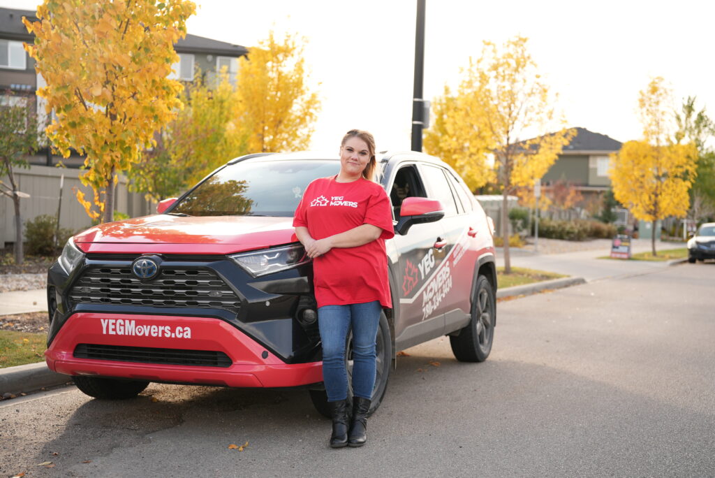 YEG Movers employee beside branded moving vehicle.