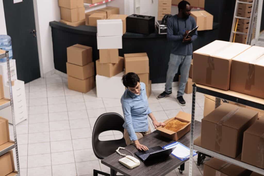 Workers organizing boxes in a warehouse office.