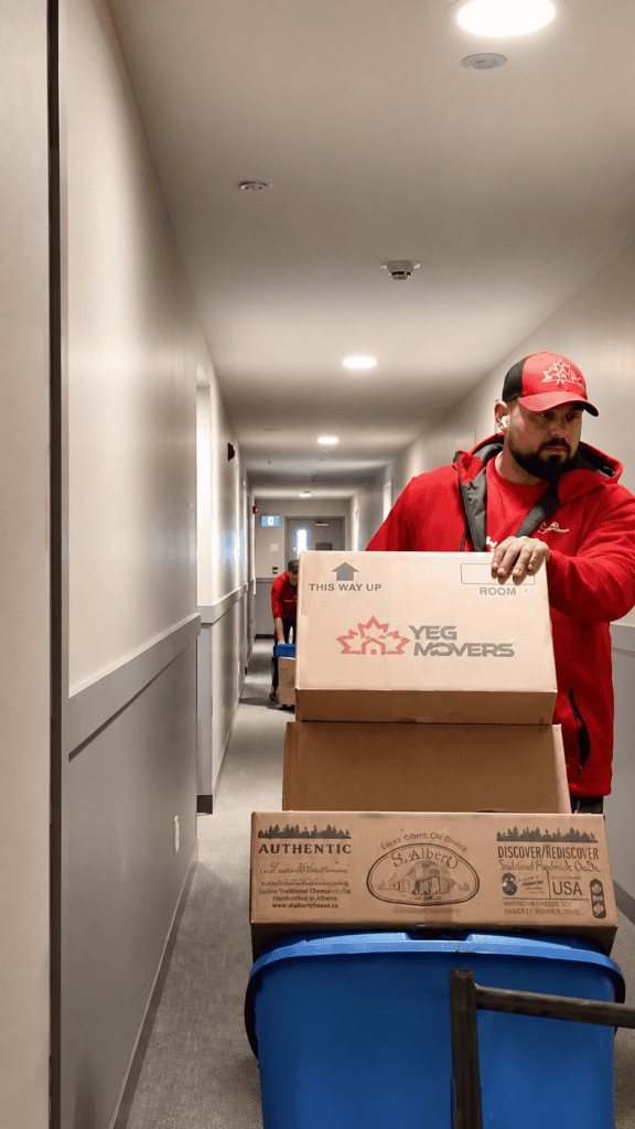 Mover pushing boxes down apartment hallway