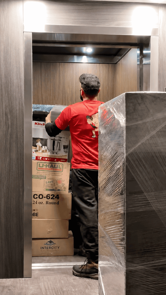 Mover loading boxes and wrapped furniture into elevator