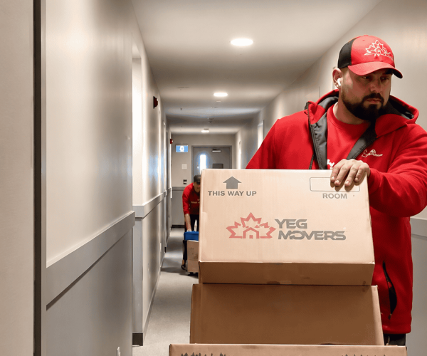 Mover pushing boxes on cart down hallway