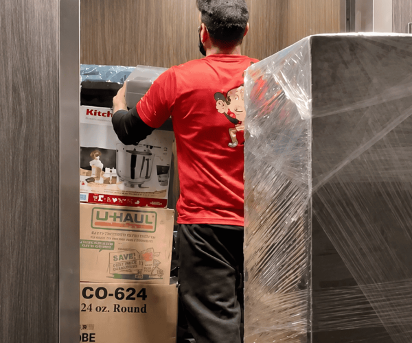 Mover loading boxes and wrapped furniture into elevator